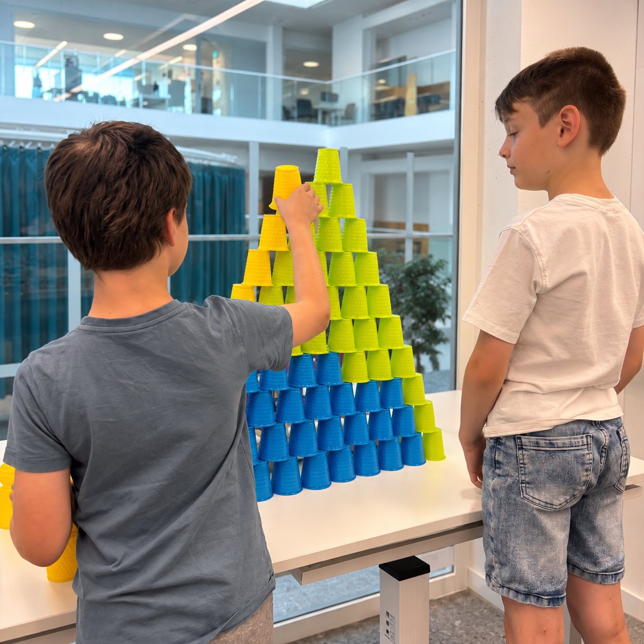Twee kinderen bouwen een piramide van bekers