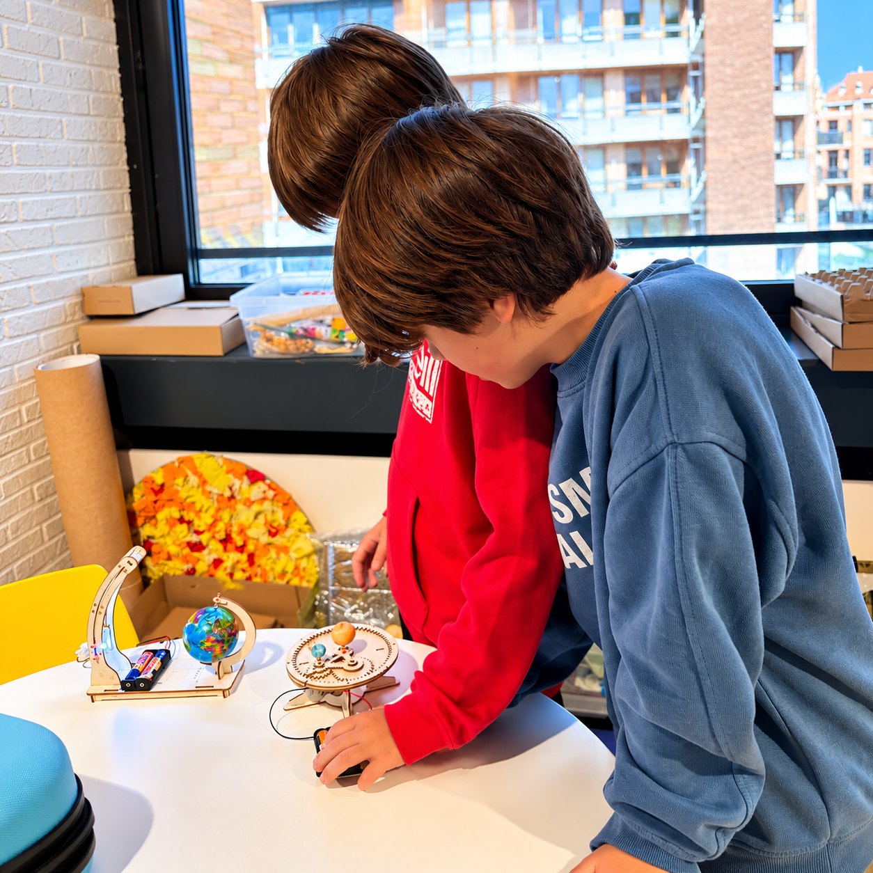 Twee kinderen buigen zich over een houten bouwpakket met een wereldbol