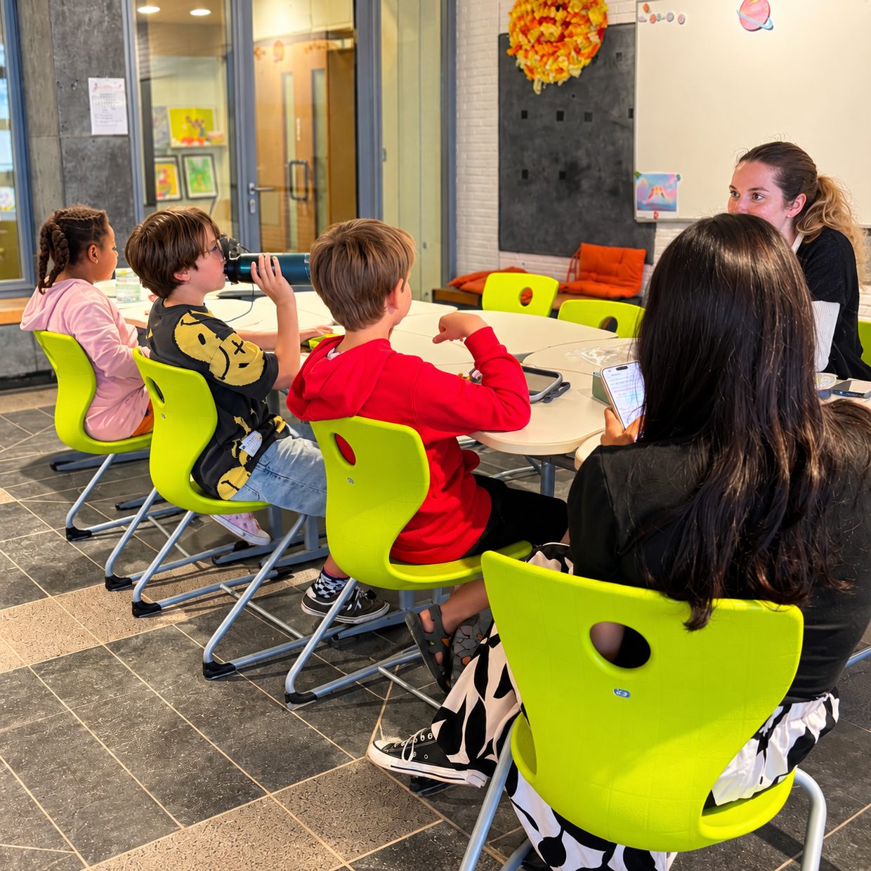 Kinderen en begeleiders zitten rond een tafel in de plusklas